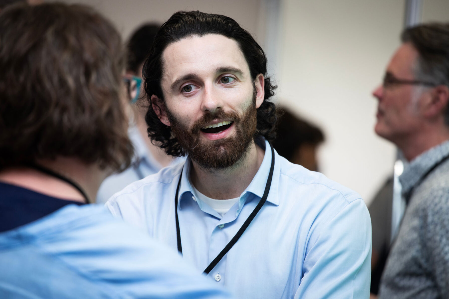 Man in a blue shirt engaged in conversation at a networking event.