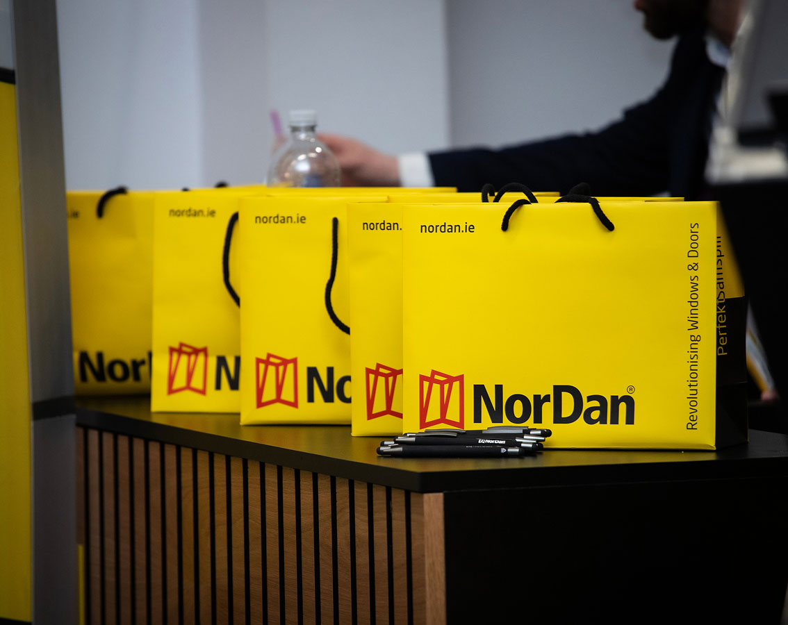 Yellow NorDan gift bags on a counter promoting windows and doors at a business event.
