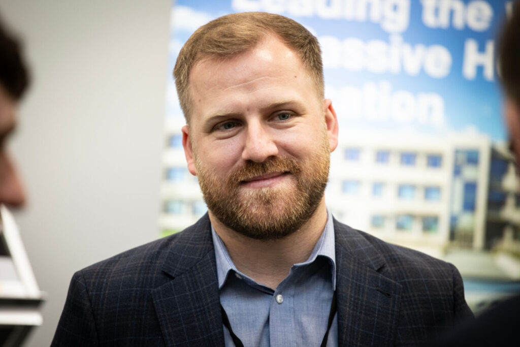 Smiling man in a business suit at a professional event background with building.