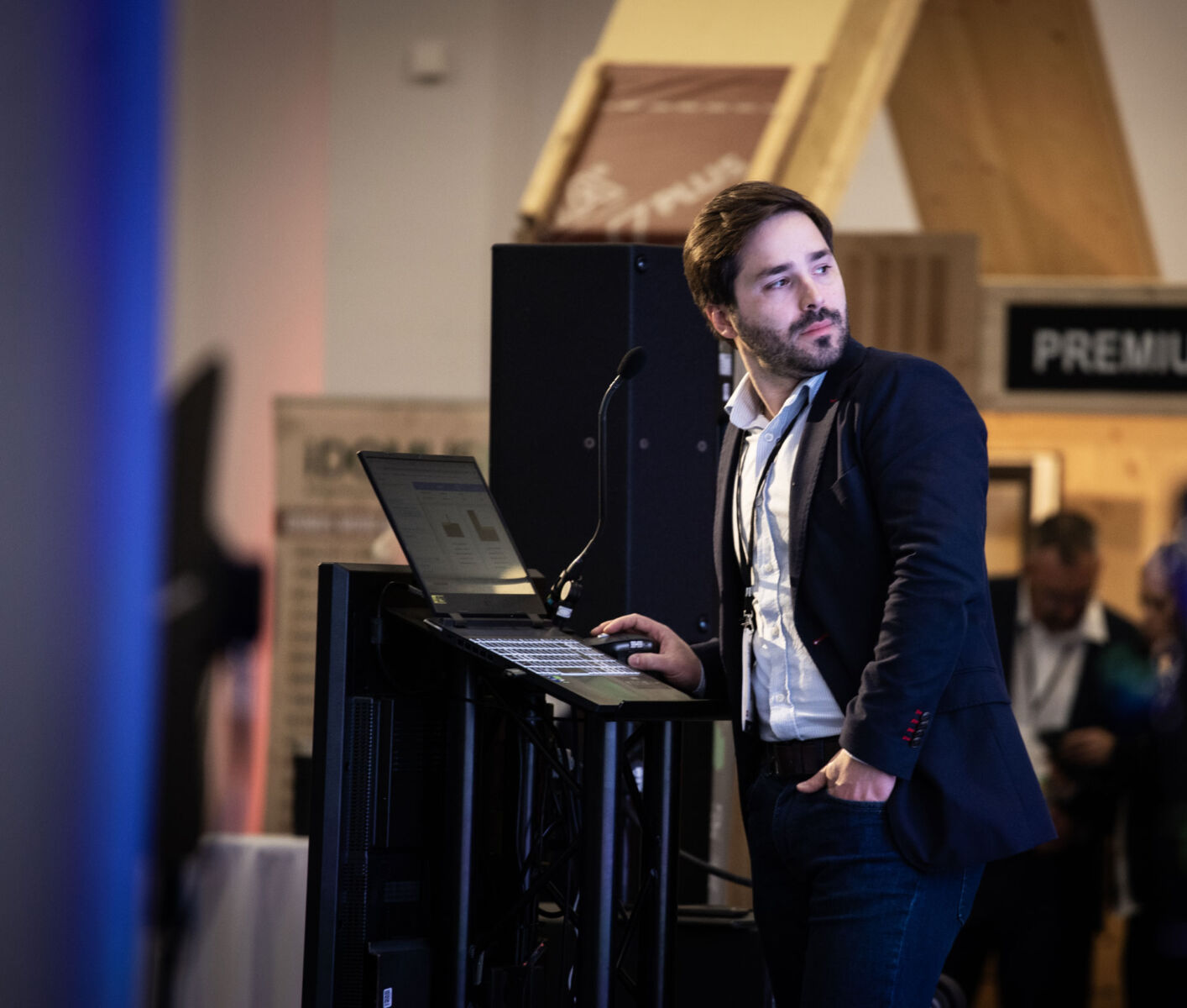 Man giving a presentation with a laptop and microphone at a conference event.