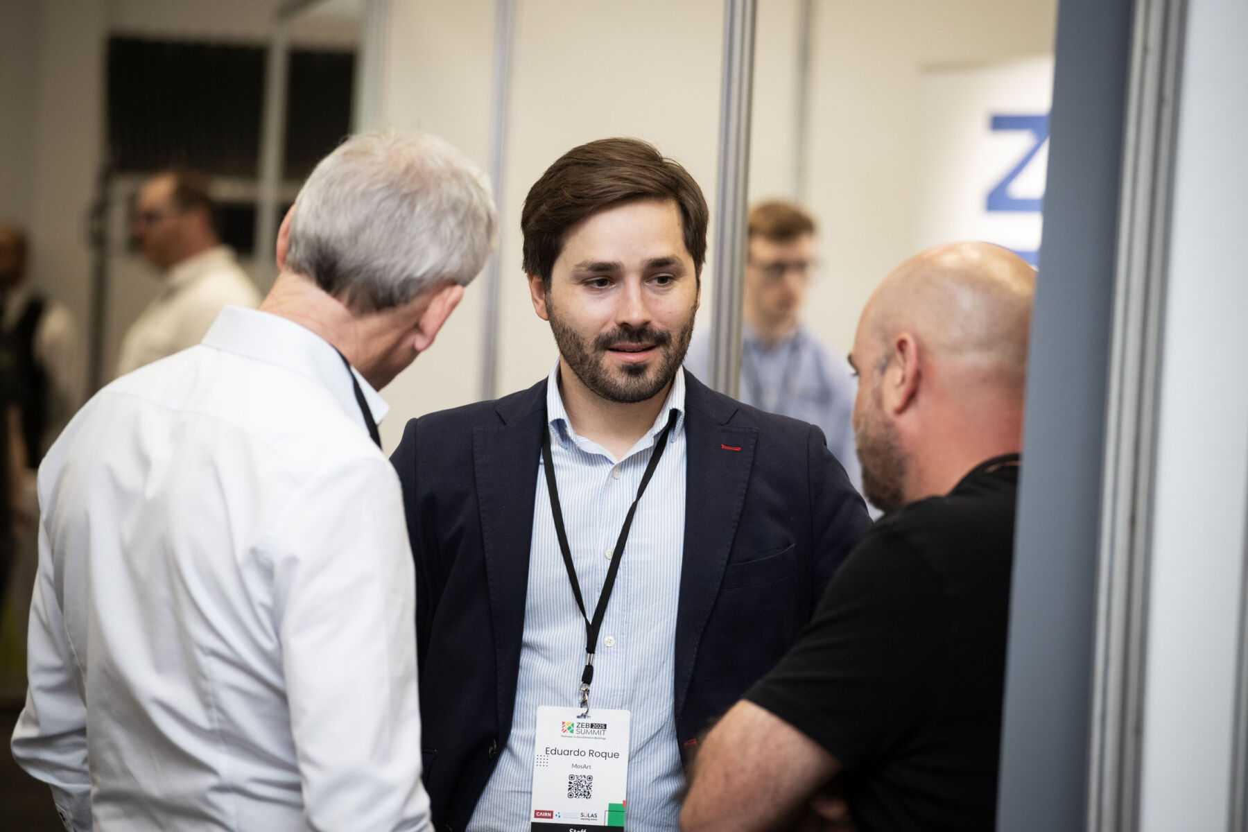 Three men engaged in conversation at a professional networking event.
